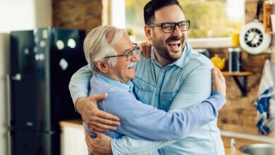 Cheerful mid adult man and his senior father embracing in the ki