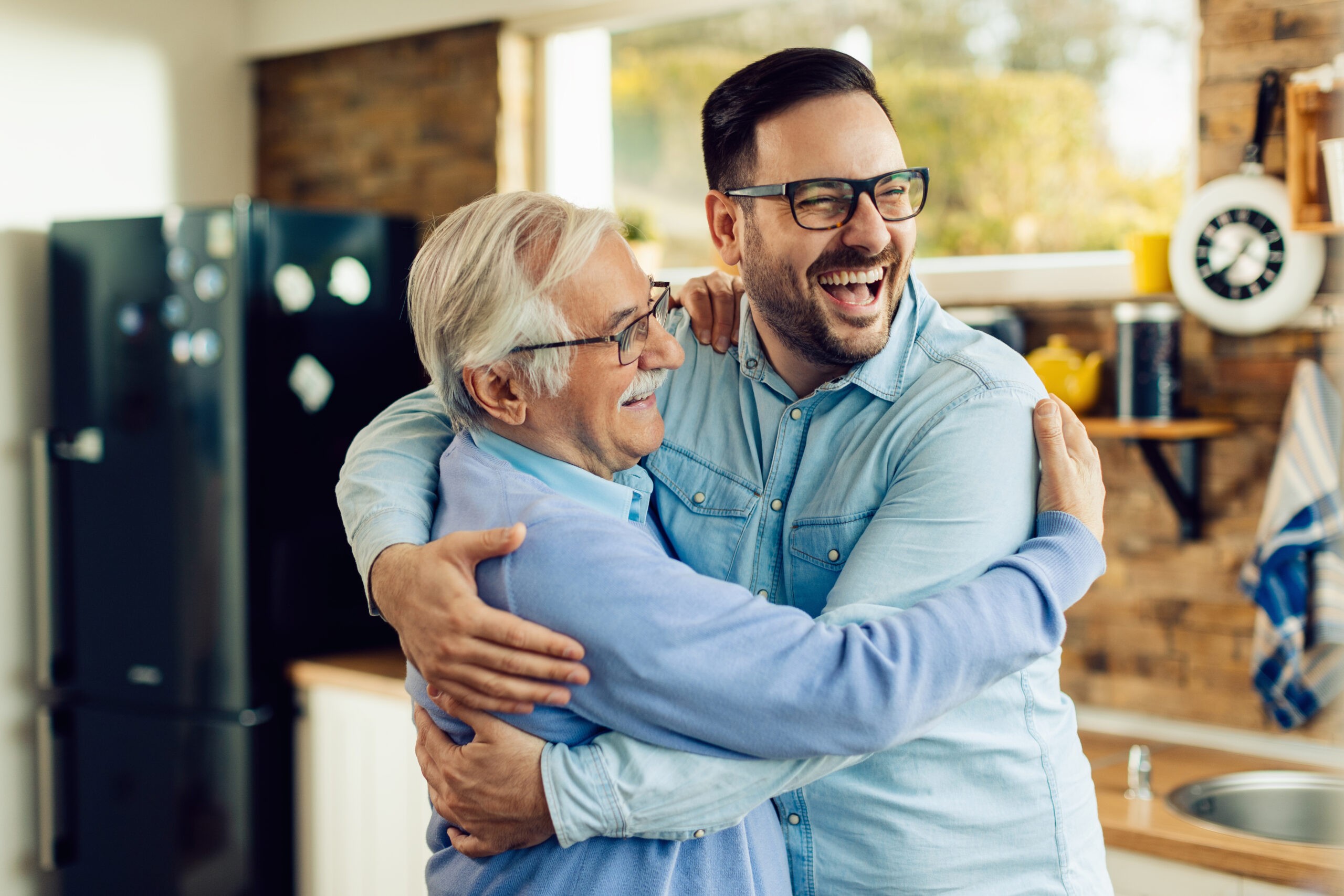 Cheerful mid adult man and his senior father embracing in the ki